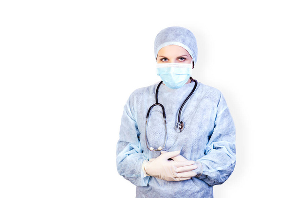 Portret młodej lekarki w mundurze medycznym w masce i gumowych, sterylnych rękawiczkach na białym, izolowanym tle. Pandemia koronawirusa. Zostań w domu.. - Zdjęcie, obraz