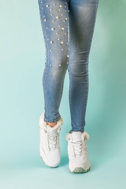 Legs of a slender girl in tight jeans and white warm sneakers. - Фото, изображение