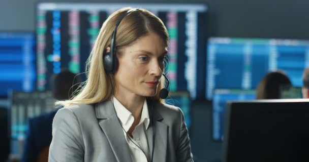 Kaukaska całkiem wesoła kobieta handlowiec w słuchawkach pracuje na monitorze komputerowym, rozmawia z klientem i ma świetny wynik w handlu. Kobieta broker świętuje wielki wynik. Szczęśliwe wieści w biurze handlowym - Materiał filmowy, wideo