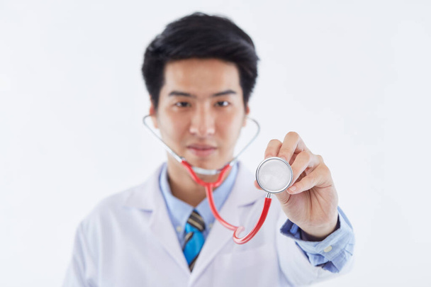 Photo of a young Good looking handsome cheerful happy man doctor posing isolated over white background with a stethoscope. - Foto, Imagem