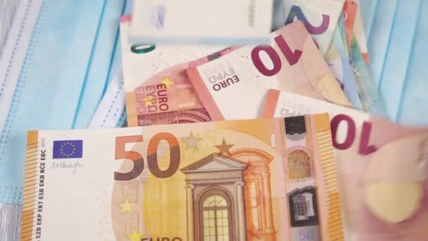Stapel von Euro-Banknoten fallen auf medizinische chirurgische Schutzmasken. Zeitlupe. Nahaufnahme - Filmmaterial, Video