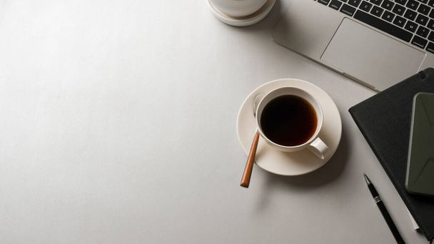 事務室のコーヒーカップ、ラップトップ、文房具、コピースペース付きの白いテーブルのトップビュー - 写真・画像