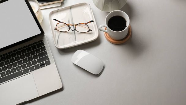 Κάτοψη χώρου εργασίας με laptop, γυαλιά, προμήθειες και φωτοτυπίες σε λευκό γραφείο  - Φωτογραφία, εικόνα