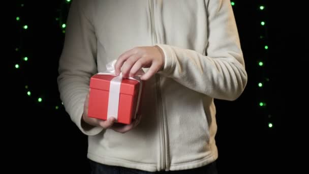 дитяча рука тримає червону коробку з білою стрічкою. Різдво, концепція нового року
 - Кадри, відео