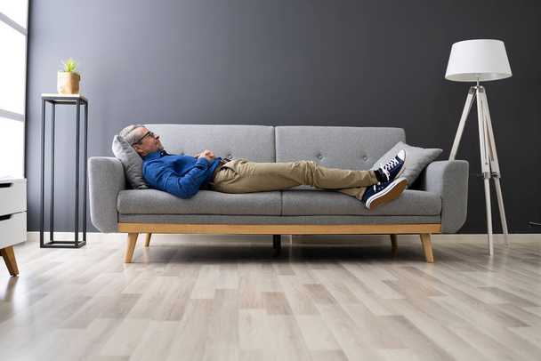 Senior Man Relaxing On Sofa In Living Room - Fotoğraf, Görsel