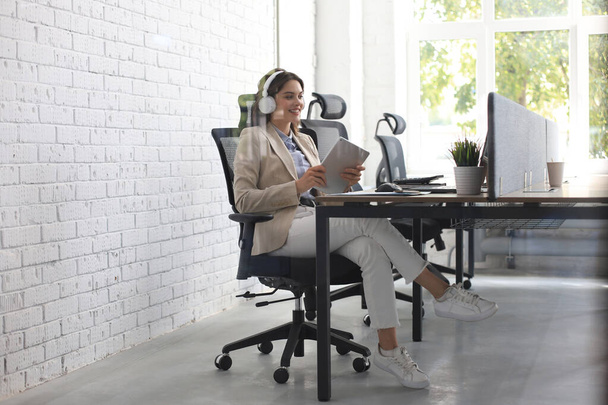 Beautiful caucasian business woman is working using laptop while sitting in creative office - Photo, Image
