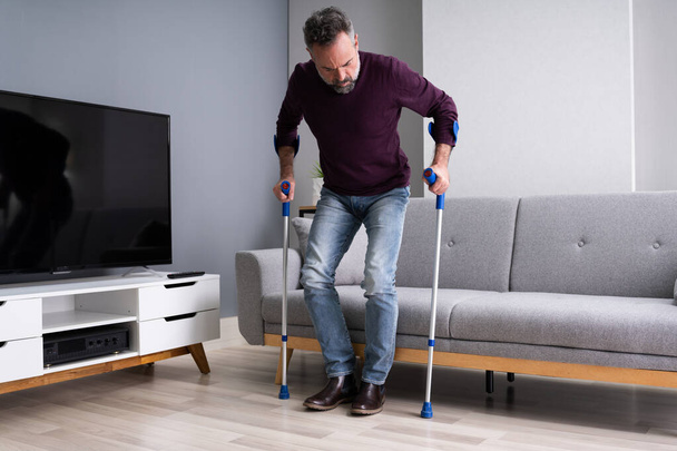 Elderly Man Using Crutches To Walk On Carpet - Фото, изображение