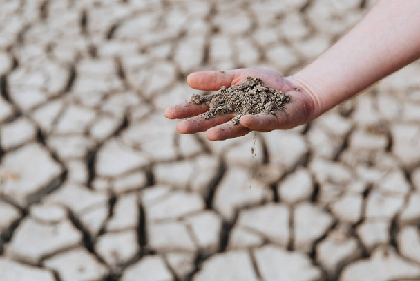 Trockene Erde liegt in der Hand eines Mannes. Erwärmung auf dem Teller. Wasserkrise.  - Foto, Bild