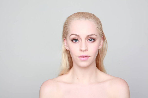 close-up portret van blonde vrouw met schone huid en blauwe ogen. geweldige studio achtergrond. - Foto, afbeelding