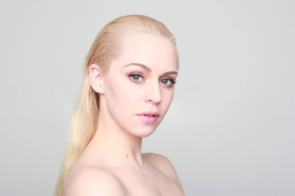 portrait rapproché de femme blonde à la peau propre et aux yeux bleus. grand arrière-plan studio. - Photo, image