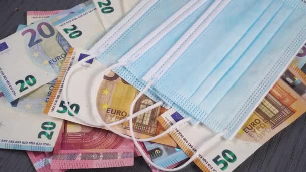 Медицинские защитные одноразовые маски на груде банкнот евро крупным планом. Долли Шот - Кадры, видео