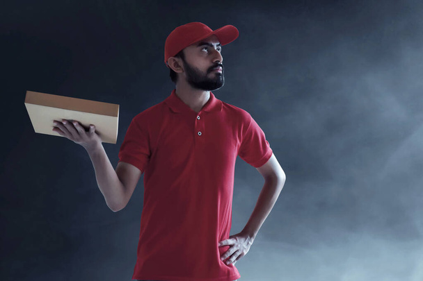 Delivery man holding cardboard box - Foto, afbeelding