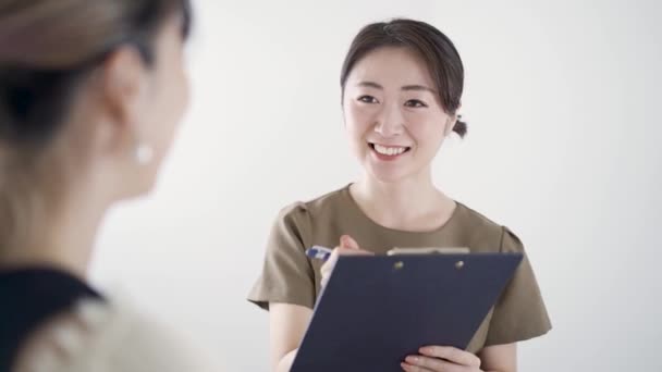 Esthéticienne japonaise offrant des conseils dans un salon de beauté à l'aide de dossiers médicaux - Séquence, vidéo