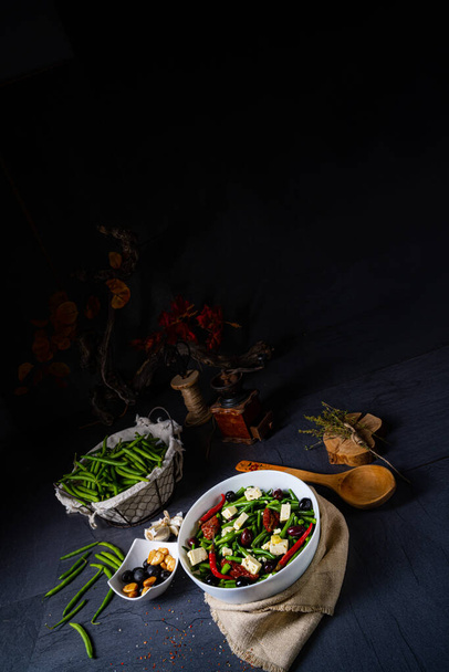 Kruidige groene bonensalade met olijven, feta kaas en gedroogde tomaten - Foto, afbeelding