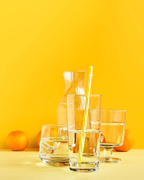 Citrusfélék torz víz és üveg sárga alapon. Művészi trendi minimalista csendélet. Egészséges életmód. C-vitamin. - Fotó, kép