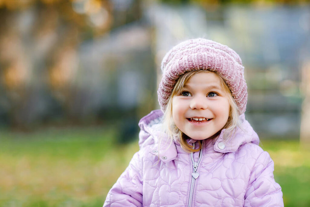 Portrait of adorable cute toddler girl of three years. Beautiful baby with blond hairs looking and smiling at the camera. Happy healthy child in winter stylish clothes outdoors. - Φωτογραφία, εικόνα