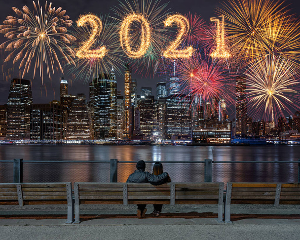 2021 escrito com fogos de artifício Sparkle com multicolor de fogos de artifício no lado de trás casal sentado e olhando New york Cityscape fundo, EUA skyline centro, Feliz ano novo e conceito de Feliz Natal - Foto, Imagem