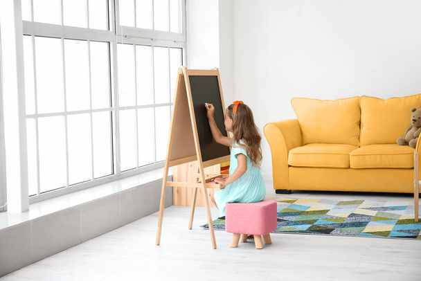 Милая маленькая девочка рисует на доске в детском саду - Фото, изображение