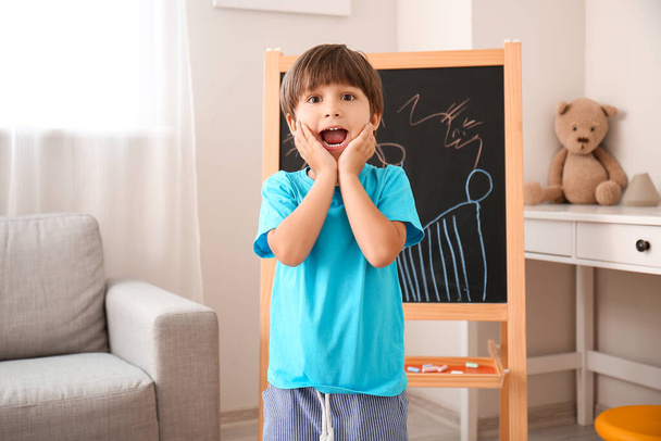 Gelukkig jongetje in de buurt geschilderd schoolbord in kleuterschool - Foto, afbeelding