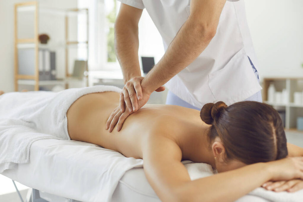Lying woman patient getting massage of back from professional chiropractor or masseur - 写真・画像