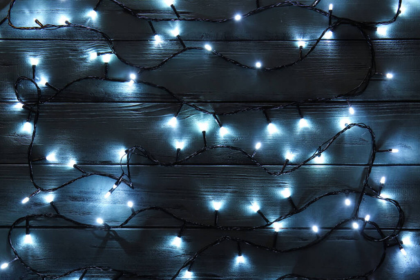 Świecące lampki na ciemnym drewnianym tle - Zdjęcie, obraz
