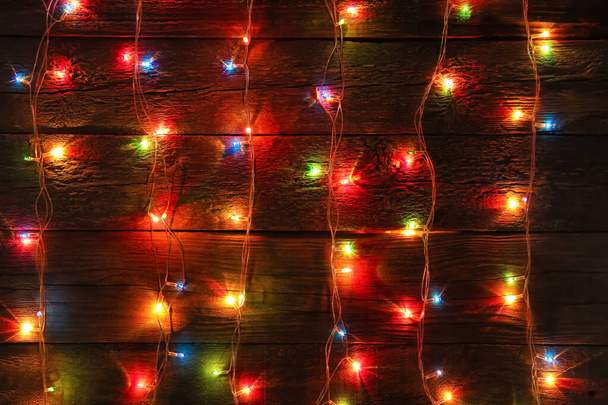 Luces de Navidad brillantes sobre fondo de madera oscura - Foto, Imagen