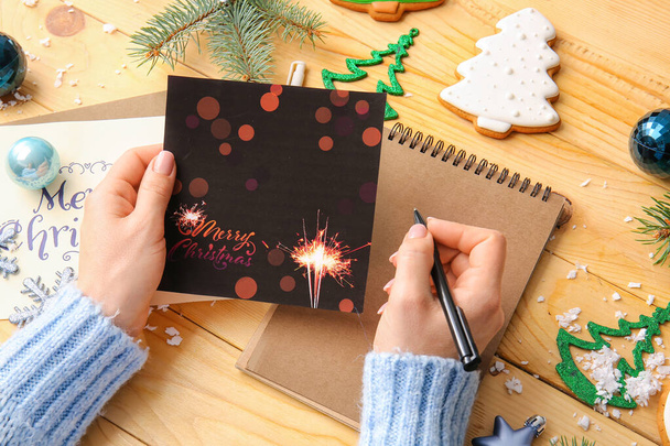Mulher escrevendo cartão postal para celebração de Natal na mesa - Foto, Imagem