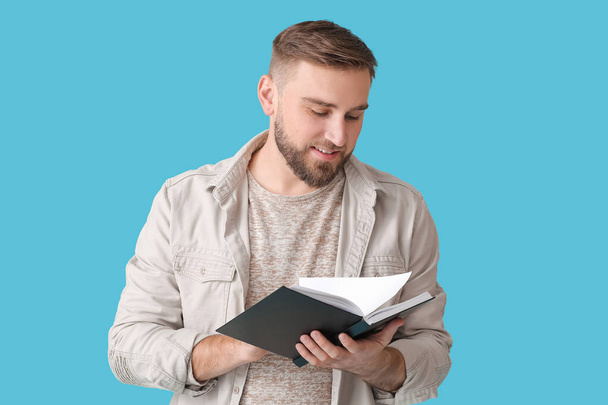 Молодой человек читает книгу на цветном фоне - Фото, изображение