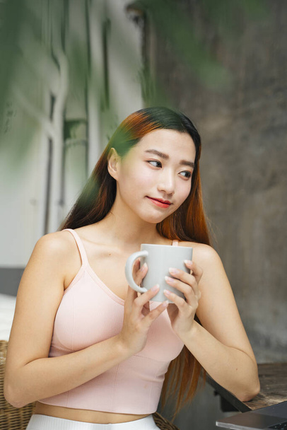 Retrato de hermosa joven asiática sosteniendo la taza de café en la cafetería. - Foto, Imagen