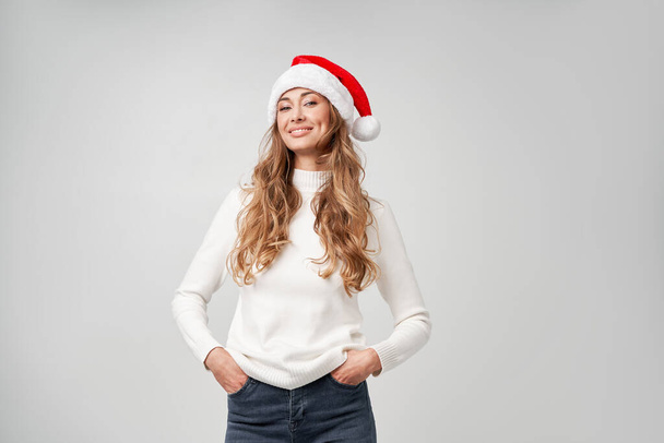 Nő karácsony Mikulás kalap pulóver fehér stúdió háttér Gyönyörű kaukázusi nő göndör haj portré Boldog ember pozitív érzelem Ünnepi koncepció Közelkép arc portré - Fotó, kép