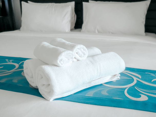 White towels on bed decoration in bedroom with pillows. Towels set and white bedding in modern hotel. - Photo, Image