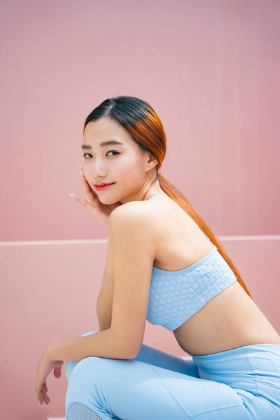 Beautiful sporty asian woman wearing sport bra on pink background. - Zdjęcie, obraz
