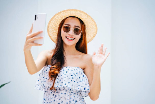 Beautiful asian traveler woman wearing sunglasses and hat vlogging with smartphone. - Foto, Bild