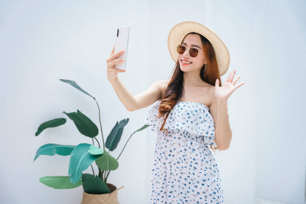 Beautiful asian traveler woman wearing sunglasses and hat vlogging or live stream with smartphone. - Fotó, kép