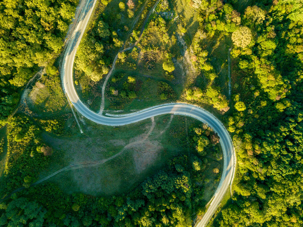 Вид с воздуха на горную дорогу, проходящую через лесной ландшафт. - Фото, изображение