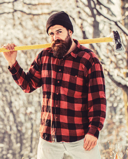 Bearded lumberjack. Brutal bearded lumberjack with ax in winter forest. Handsome man, hipster in snowy forest. Lumberjack with an ax in his hands. Male holds an ax on a shoulder. Brutal bearded man - Photo, Image