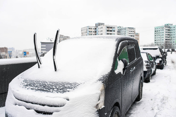 Stěrače aut pokryté ledem a sněhem po zamrznutí deště zblízka. Ledová bouře v listopadu, Vladivostok, Rusko. Město v zimě. Sněhové počasí. Zimní mrazivé scény. - Fotografie, Obrázek