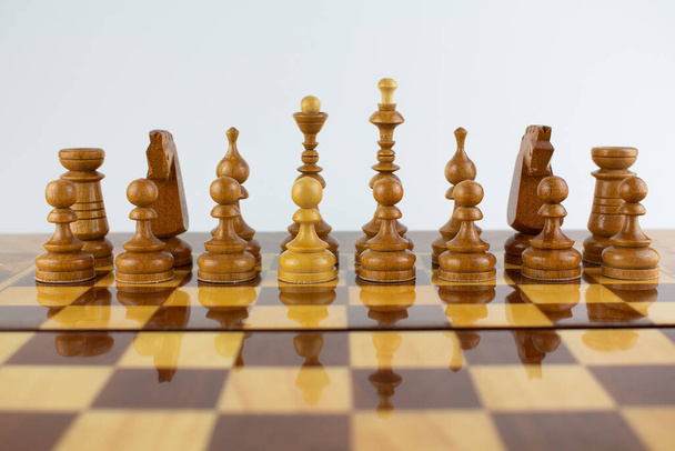 a white pawn among black chess pieces - Foto, Imagen