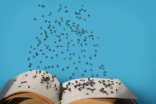 Письма алфавита в левитации в воздухе над открытыми страницами книги - Фото, изображение