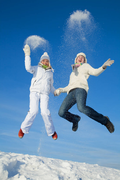 young couple having fun jumping on snowy hill in winter - Фото, зображення