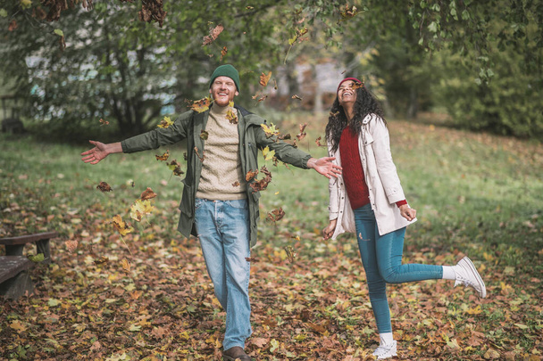 Young couple enjoying playing with beautiful autumn leaves - Foto, Imagen