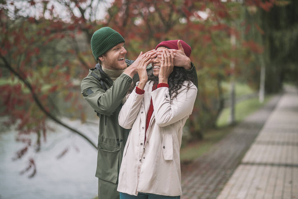 Man closing womans eyes while walking in a park - Foto, afbeelding