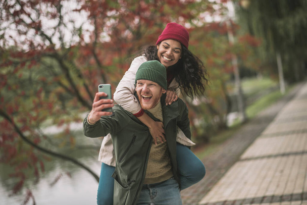 Smiling partners making emotional selfies in the autumn park - Foto, Imagen