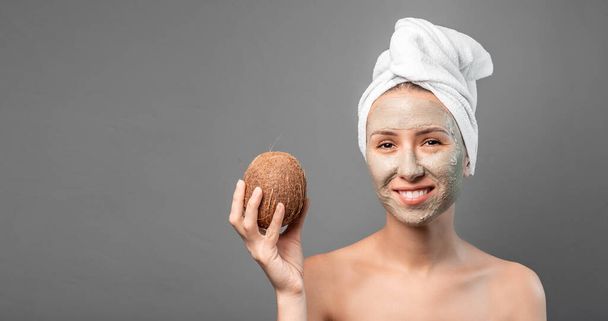 Mujer con máscara de coco fresco aplicado en la cara. Cuidado de la piel, limpieza, cosmética orgánica. Formato de banner largo. espacio para texto. - Foto, Imagen