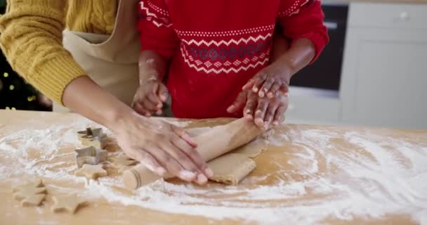 Primer plano de las manos femeninas afroamericanas con un niño pequeño y lindo en la mesa en la cocina casera haciendo masa para galletas. Pequeño niño ayudando a mamá a hornear galletas de Navidad. Concepto de preparación para vacaciones - Metraje, vídeo