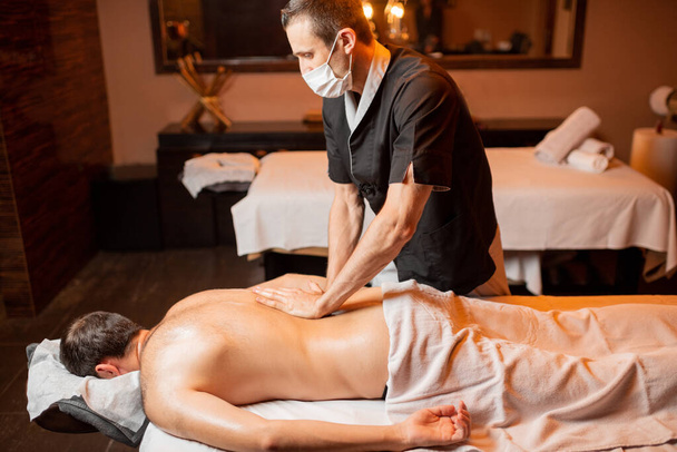 Masseur doing a deep massage to a male client - Photo, Image