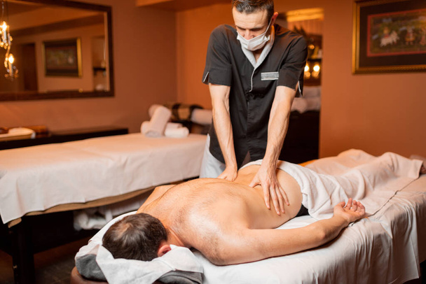 Masseur doing a deep massage to a male client - Photo, Image