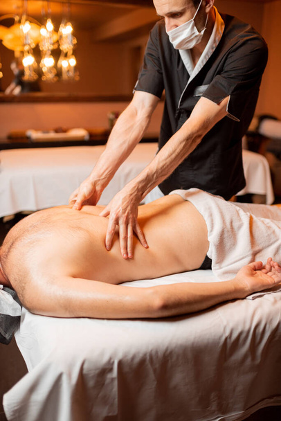 Masajista haciendo un masaje profundo a un cliente masculino - Foto, imagen
