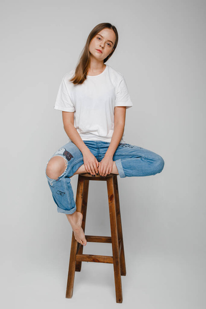 modeltests. mooi meisje met lang haar zitten op stoel en poseren - Foto, afbeelding