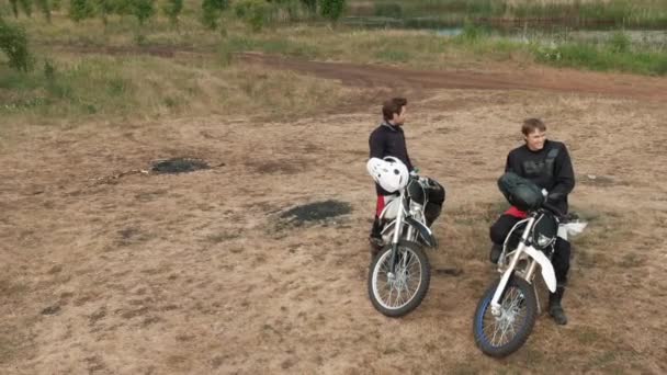 Drone disparo de hombres alegres en motocicletas descansando después del paseo y disfrutando de la naturaleza - Imágenes, Vídeo